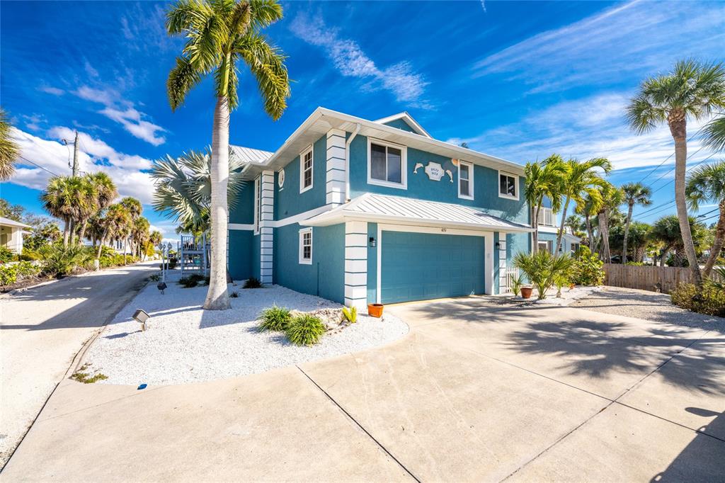 A two-story teal house with a metal roof and a concrete driveway sits among palm trees — 4151 N BEACH ROAD, ENGLEWOOD, FL
