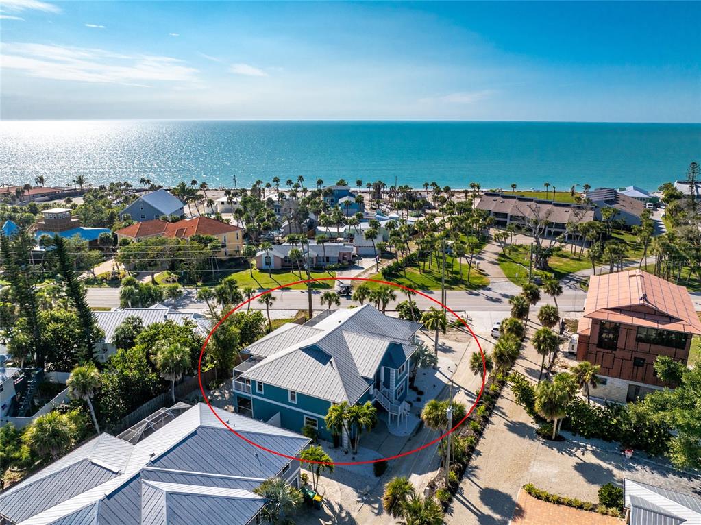 An aerial view shows a blue house with a metal roof near the ocean — 4151 N BEACH ROAD, ENGLEWOOD, FL