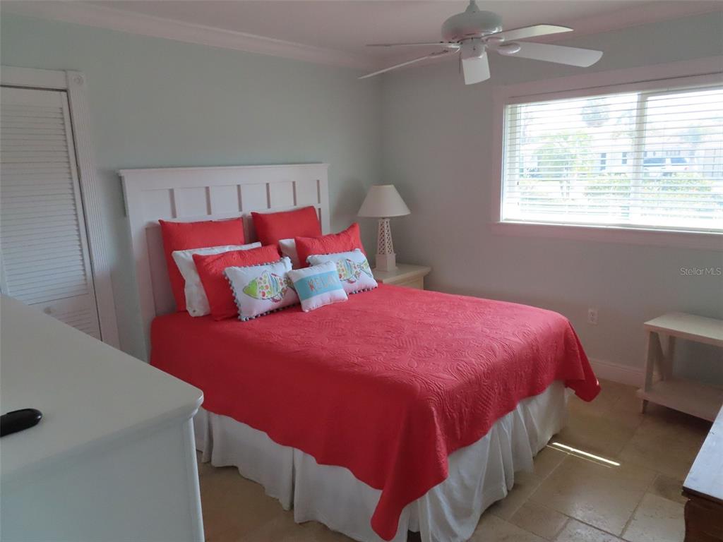 A bedroom features a bed with a red quilt, white headboard, and a ceiling fan — 513 GUNWALE LANE, LONGBOAT KEY, FL