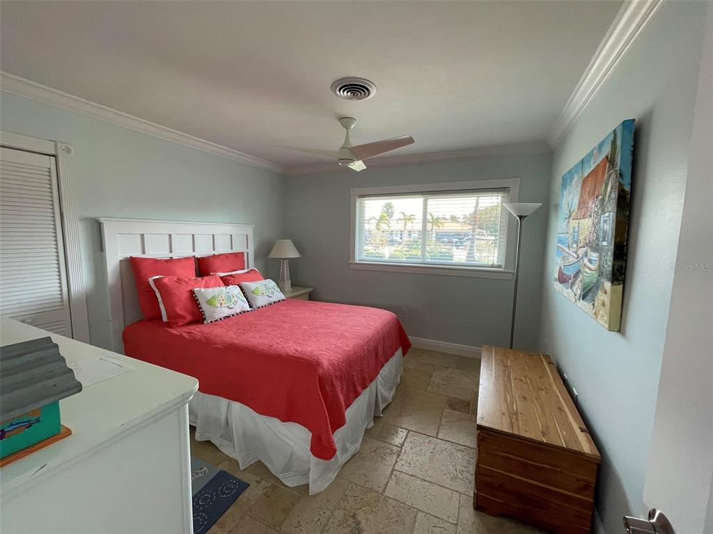 A bedroom features a red bed, tile flooring, a ceiling fan, and a wall painting — 513 GUNWALE LANE, LONGBOAT KEY, FL