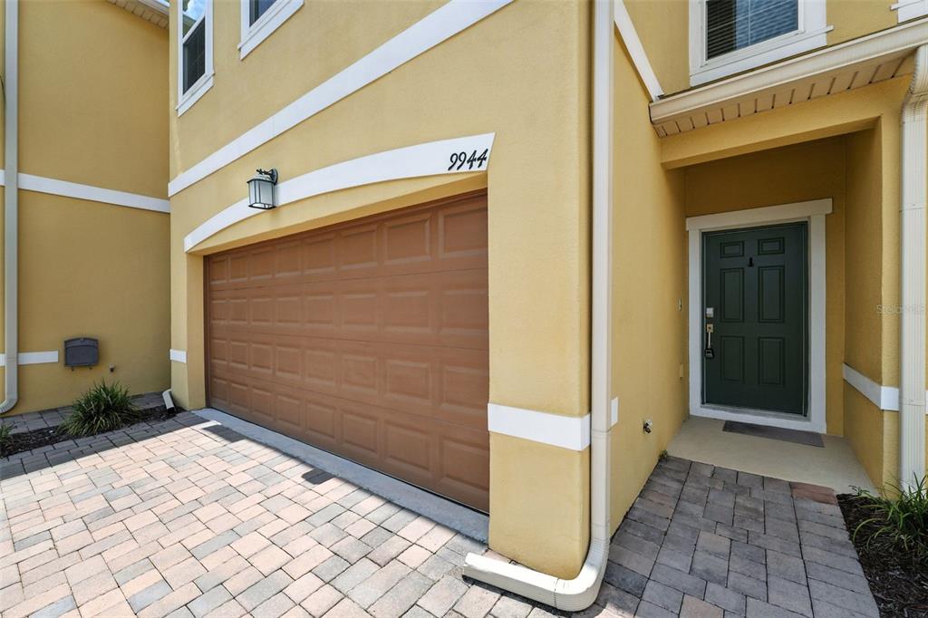 A yellow two-story townhouse exterior features a brown garage door and a dark green door — 9944 RED EAGLE DRIVE, ORLANDO, FL