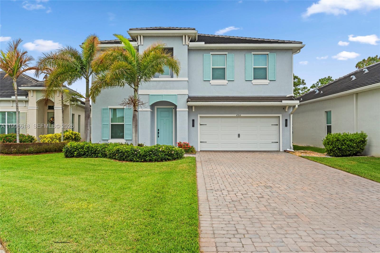 A two-story house with a light blue exterior, white garage, and a paved driveway — 4764 SW Briarwood Ct, Stuart FL 34997, STUART, FL