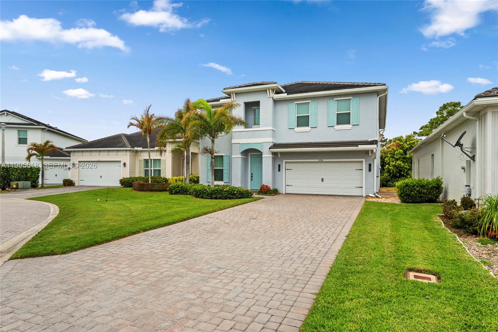 A two-story light blue house with a paved driveway and palm trees in the front yard — 4764 SW Briarwood Ct, Stuart FL 34997, STUART, FL