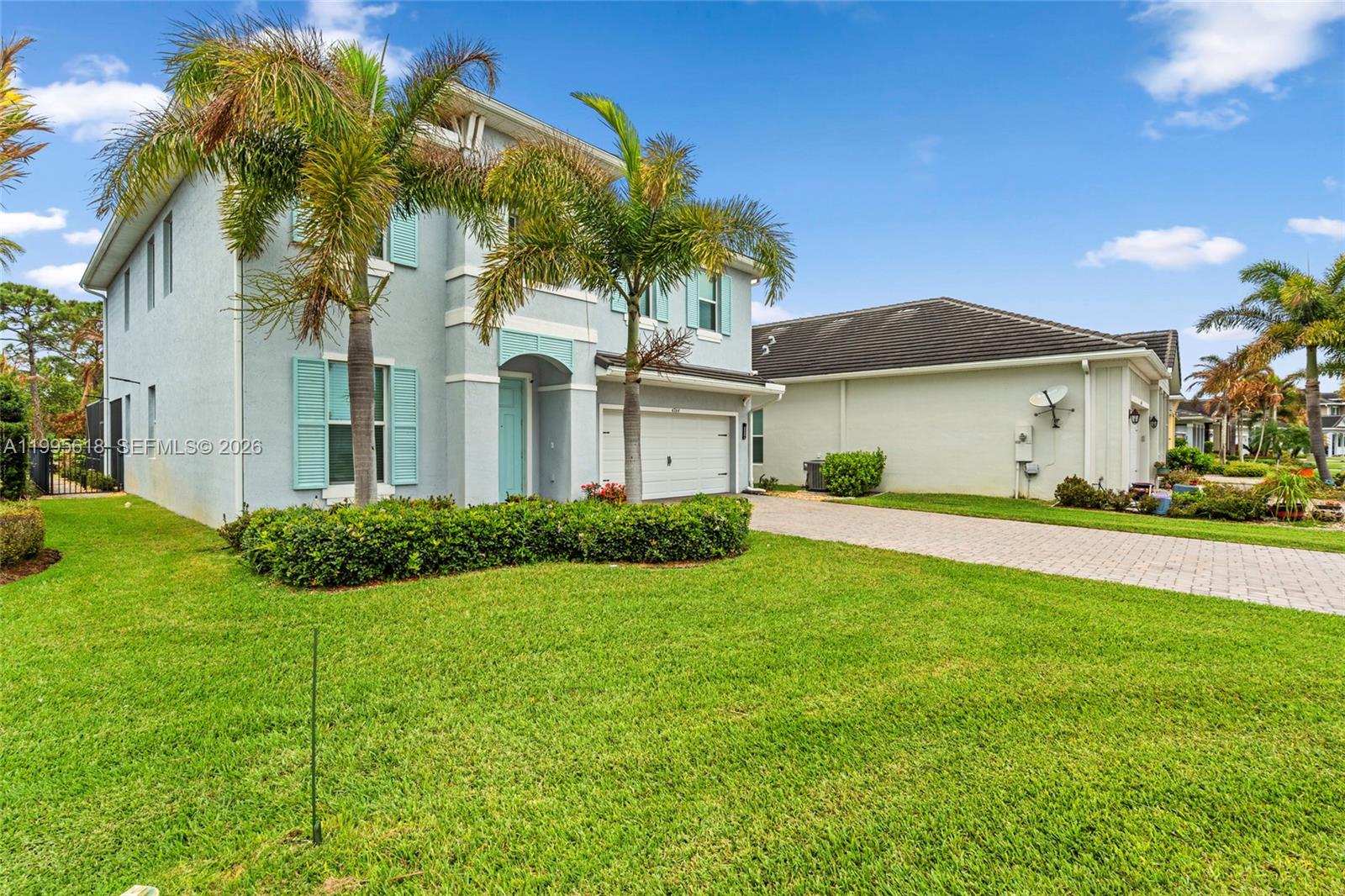 A two-story light blue house with a white garage and palm trees in the front yard — 4764 SW Briarwood Ct, Stuart FL 34997, STUART, FL