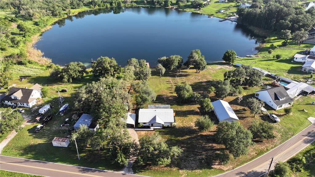An aerial view shows a white house with a metal roof, front porch, and carport — 1100 GOLDEN BOUGH ROAD, LAKE WALES, FL