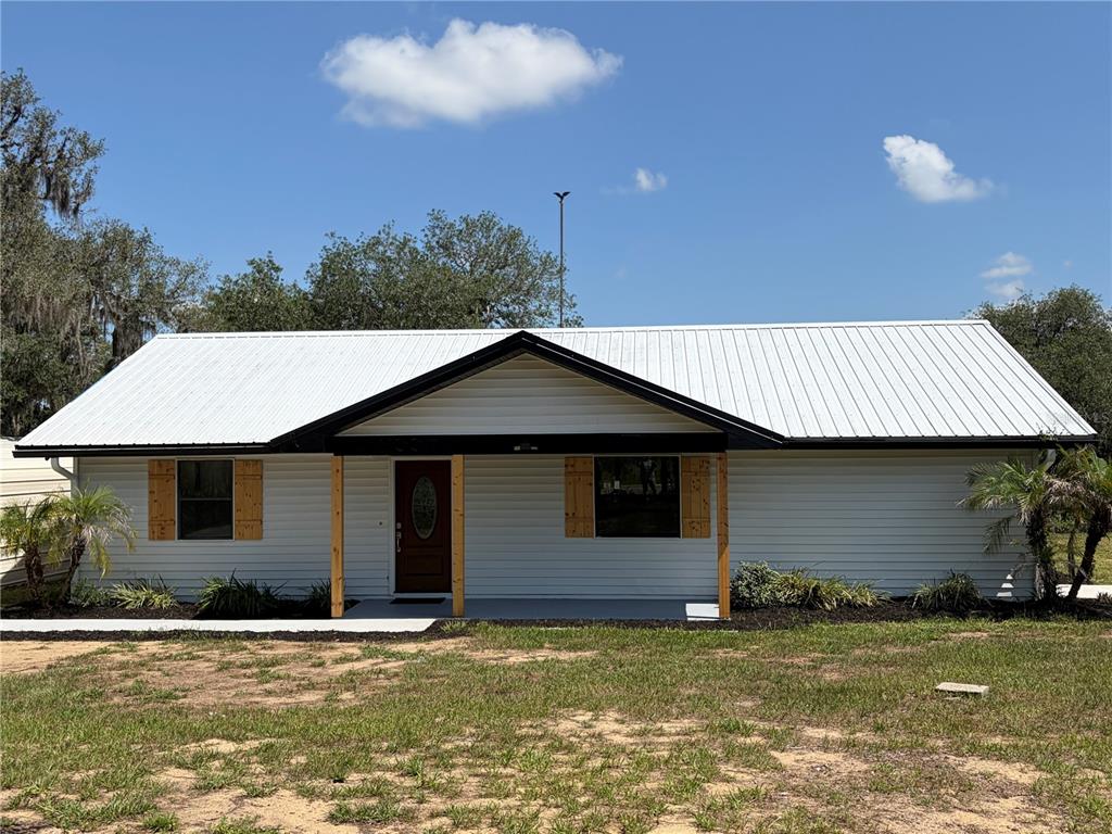 An aerial view shows a house with a metal roof situated near a large lake — 1100 GOLDEN BOUGH ROAD, LAKE WALES, FL