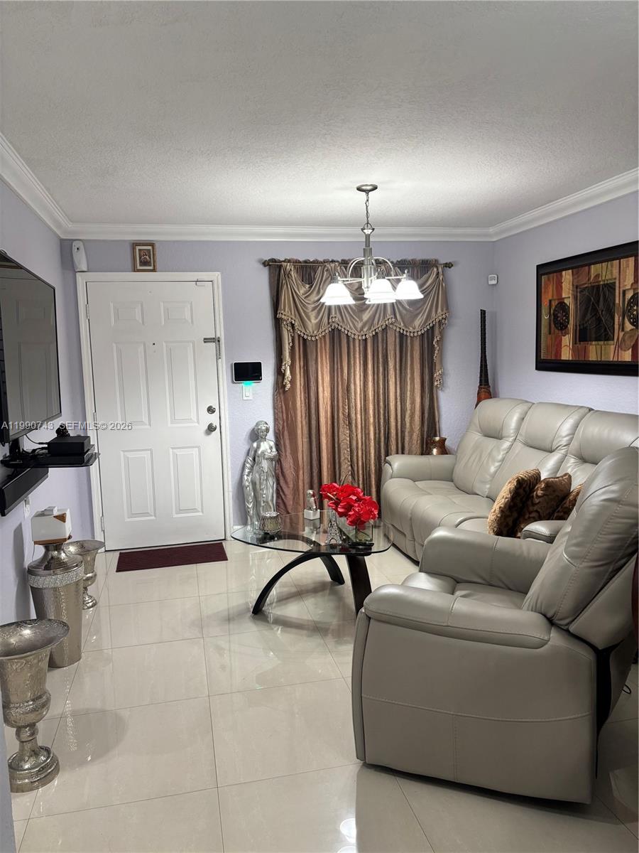 A living room features light-colored tile floors, a grey leather sofa, and a glass coffee table — 2310 W 74th St # 103, Hialeah FL 33016, HIALEAH, FL