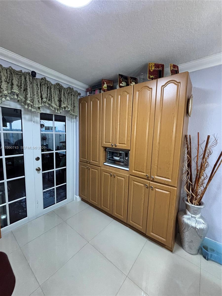 A kitchen features light wood cabinetry, a built-in microwave, and tile flooring — 2310 W 74th St # 103, Hialeah FL 33016, HIALEAH, FL