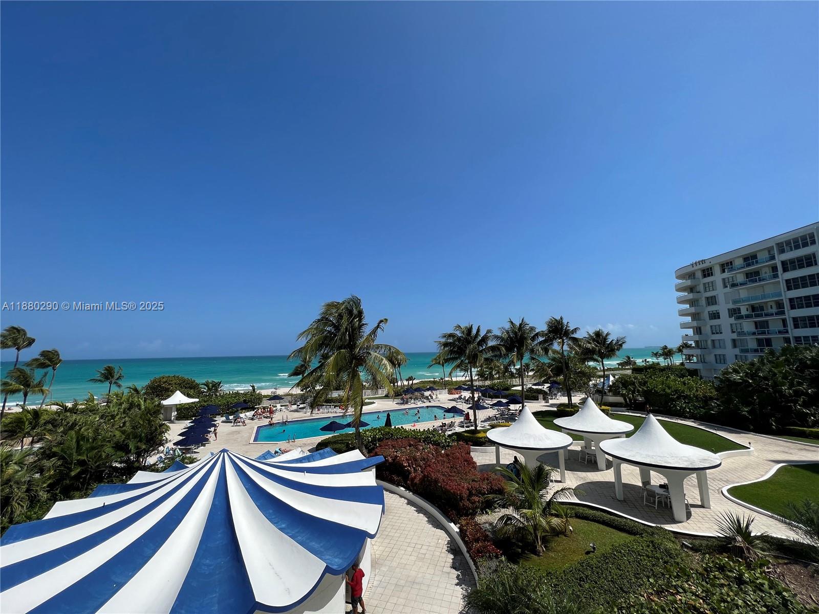 An elevated view shows a swimming pool, beach, and resort grounds with blue-and-white cabanas — 5161 Collins Ave # 514, Miami Beach FL 33140, MIAMI BEACH, FL