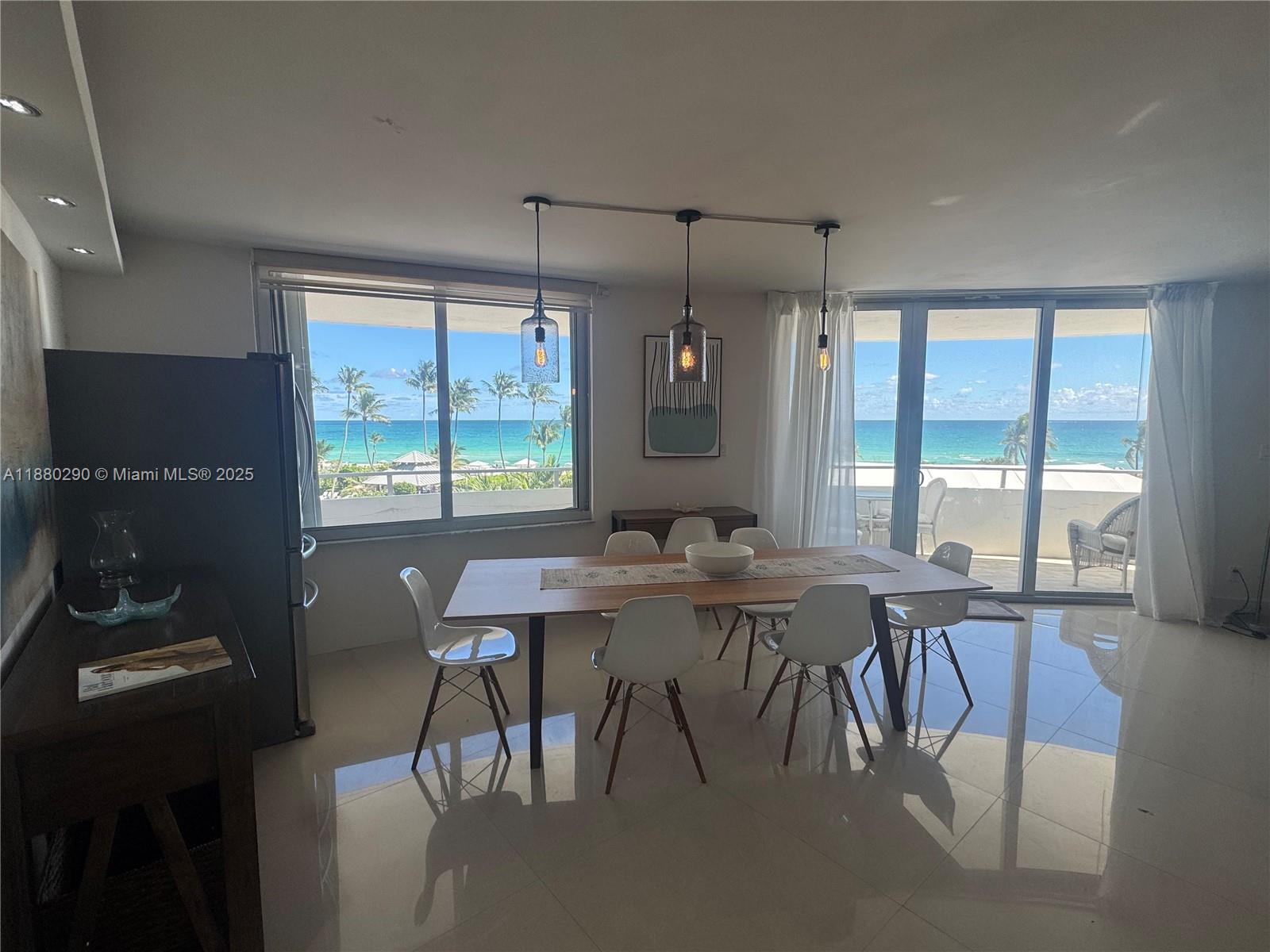 A dining room with a wooden table, white chairs, and floor-to-ceiling ocean views — 5161 Collins Ave # 514, Miami Beach FL 33140, MIAMI BEACH, FL