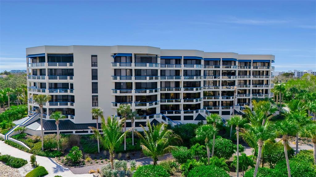 An exterior view of a multi-story apartment building surrounded by palm trees and landscaping — 2110 HARBOURSIDE DRIVE UNIT 523, LONGBOAT KEY, FL