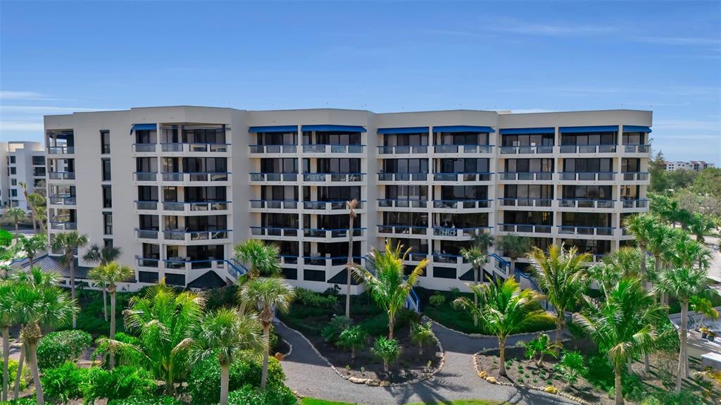 An exterior view of a multi-story apartment building surrounded by palm trees and landscaping — 2110 HARBOURSIDE DRIVE UNIT 523, LONGBOAT KEY, FL