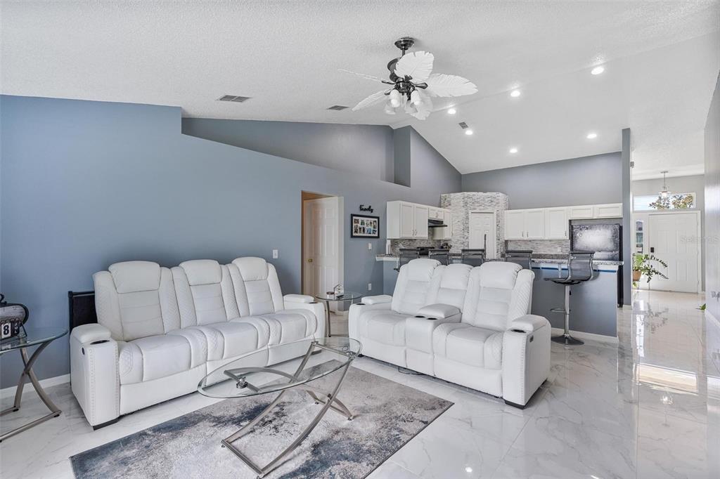A living room with white reclining sofas, a glass coffee table, and tile flooring — 1961 SAWFISH DRIVE, KISSIMMEE, FL