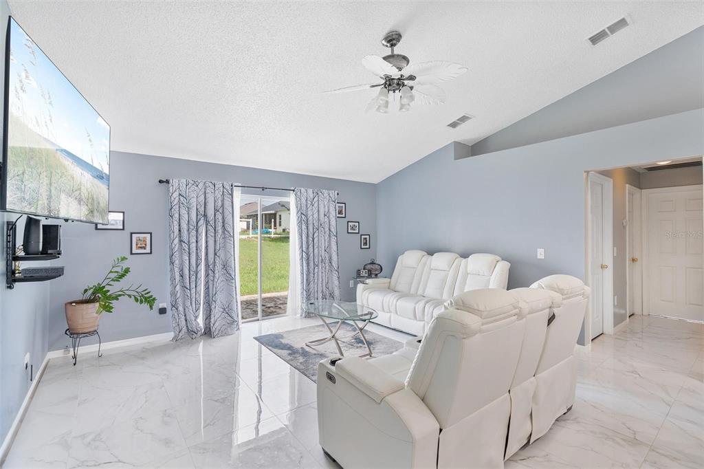 A living room features white leather sofas, a glass coffee table, and light-colored tile floors — 1961 SAWFISH DRIVE, KISSIMMEE, FL