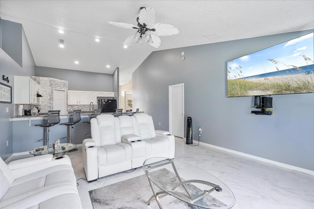 A living room features white leather reclining furniture, a glass coffee table, and a wall-mounted television — 1961 SAWFISH DRIVE, KISSIMMEE, FL