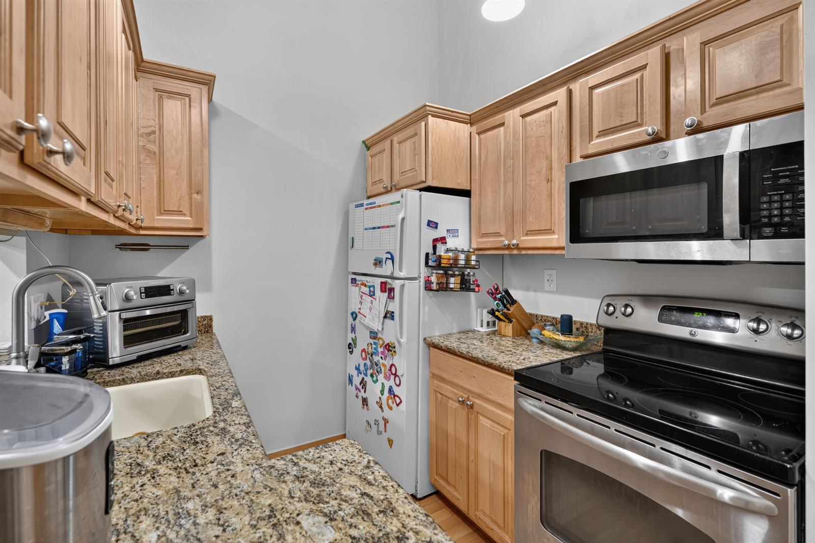 A kitchen features light wood cabinets, granite countertops, stainless steel appliances, and a white refrigerator — 6258 Chasewood Drive # G, Jupiter FL 33458, JUPITER, FL