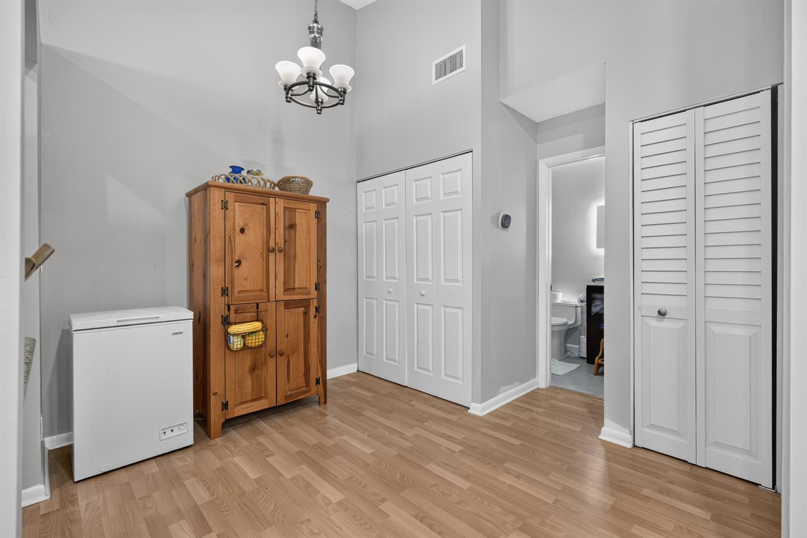 A room with wood-look flooring, a chest freezer, a wooden cabinet, and two closet doors — 6258 Chasewood Drive # G, Jupiter FL 33458, JUPITER, FL