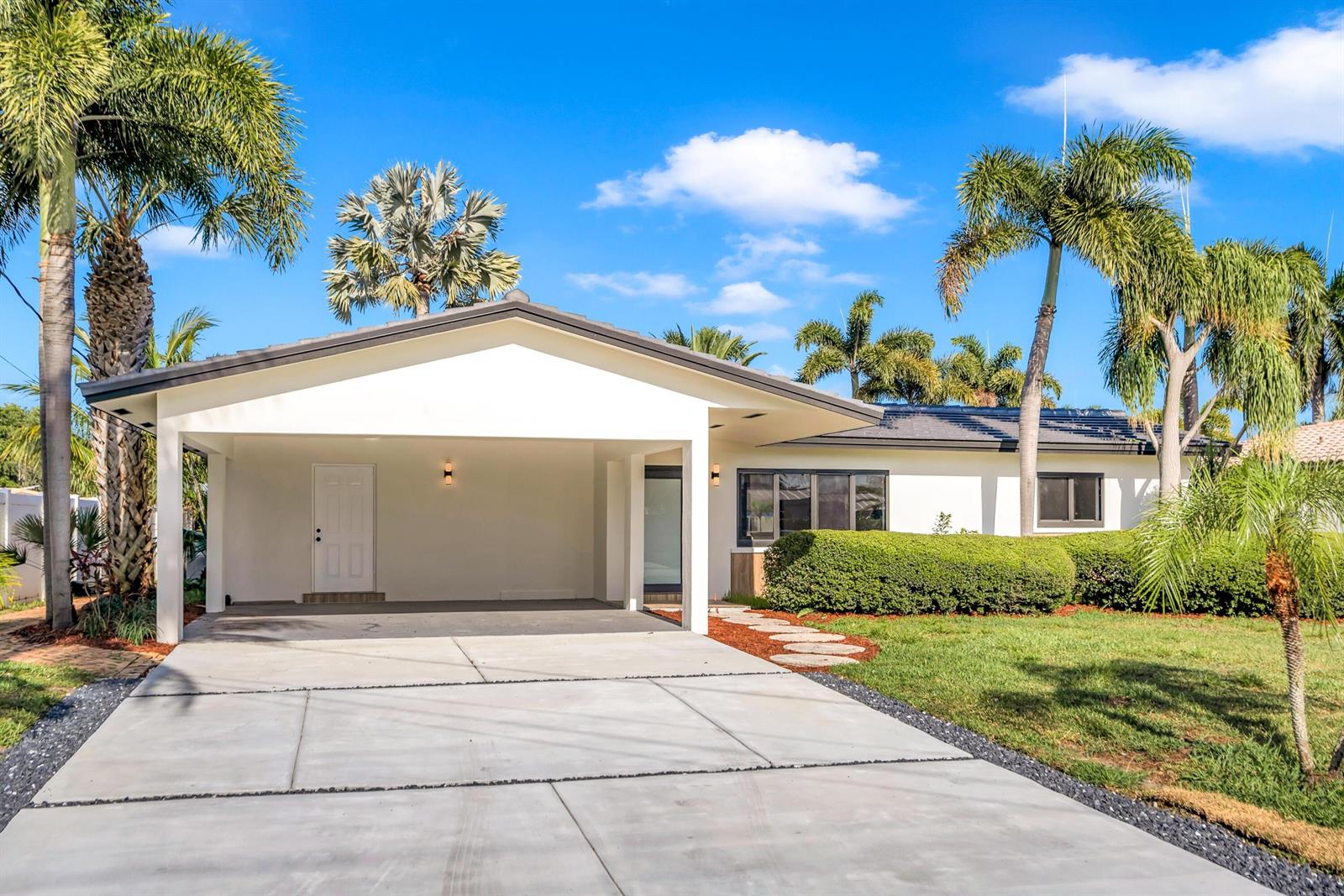 A white single-story house features a large carport, palm trees, and a concrete driveway — 1120 SE 9th Avenue, Pompano Beach FL 33060, POMPANO BEACH, FL