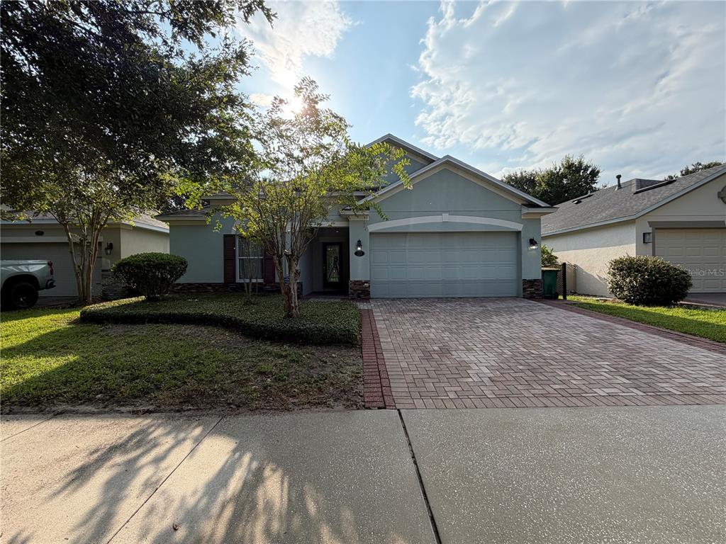 A single-story house with a paved driveway, a two-car garage, and a landscaped front yard — 115 GLADESDOWN COURT, DELAND, FL