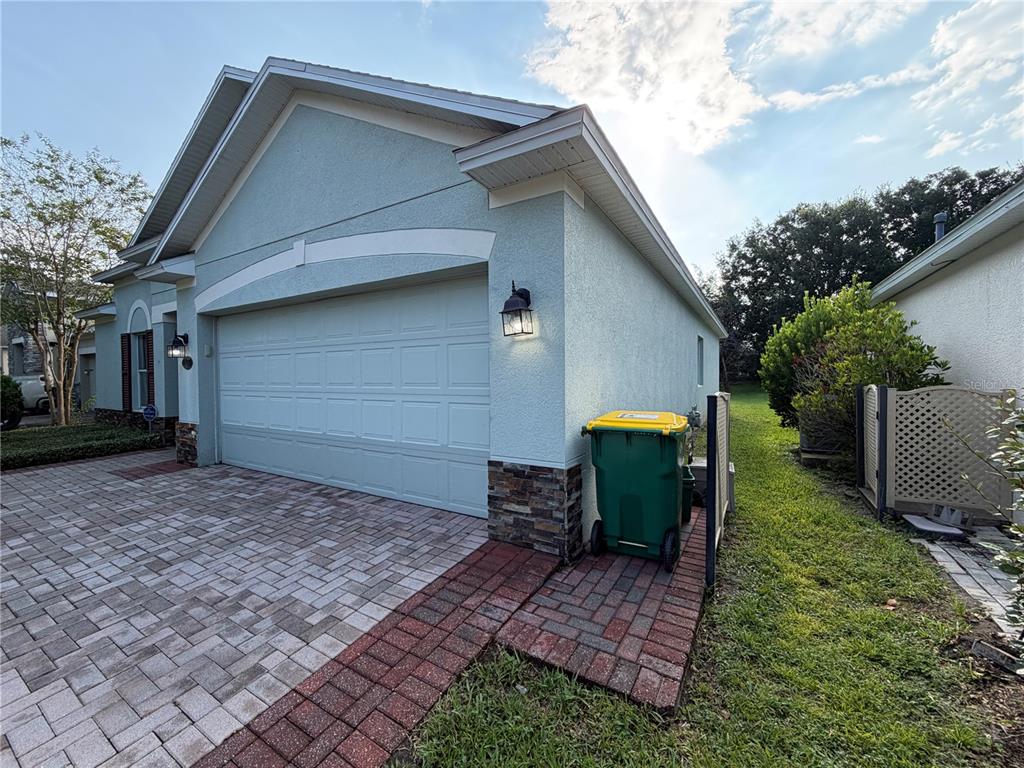 A light-colored house exterior features a two-car garage, stone accents, and a paved driveway — 115 GLADESDOWN COURT, DELAND, FL