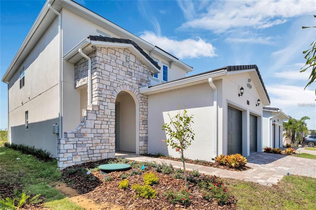 A two-story house exterior with a stone-accented entryway, a two-car garage, and landscaped front yard — 15730 VETTA DRIVE, MONTVERDE, FL