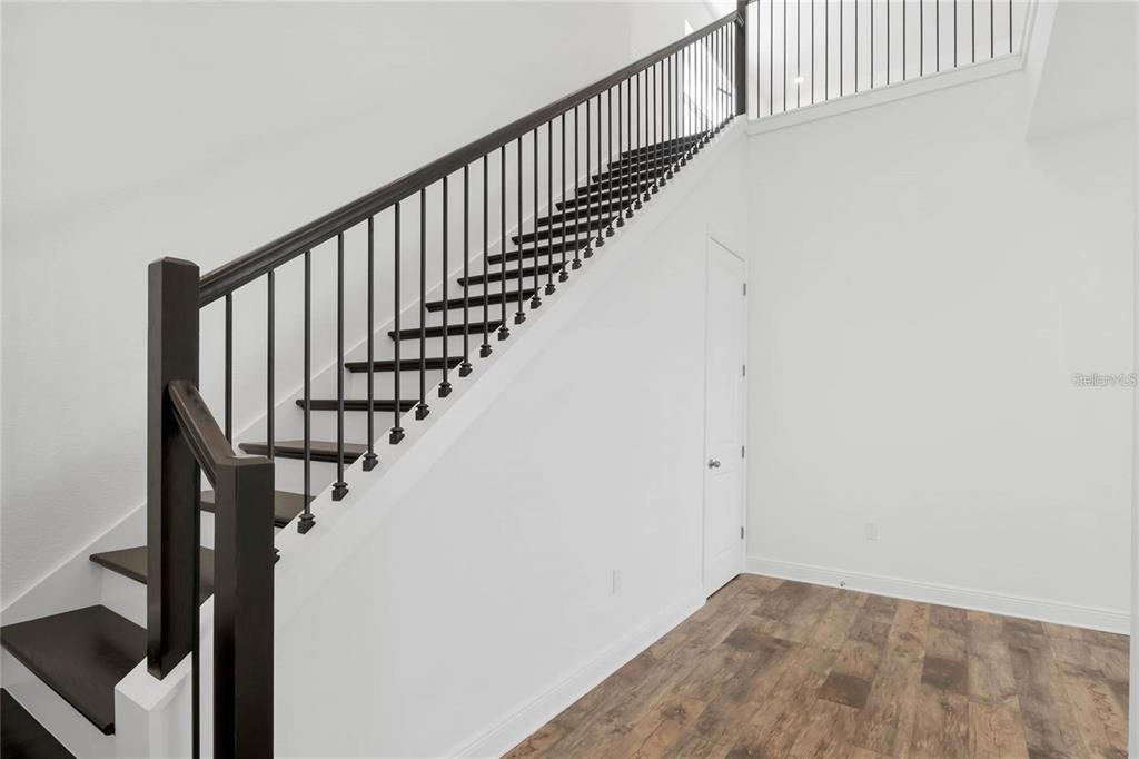 A staircase with dark wood treads and a black metal railing leads to an upper level — 15730 VETTA DRIVE, MONTVERDE, FL