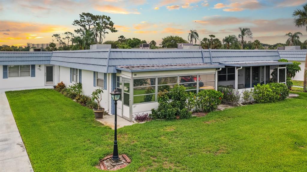 A single-story residential building with a blue metal roof and a screened-in porch — 1901 ANDOVER WAY UNIT 38, SUN CITY CENTER, FL