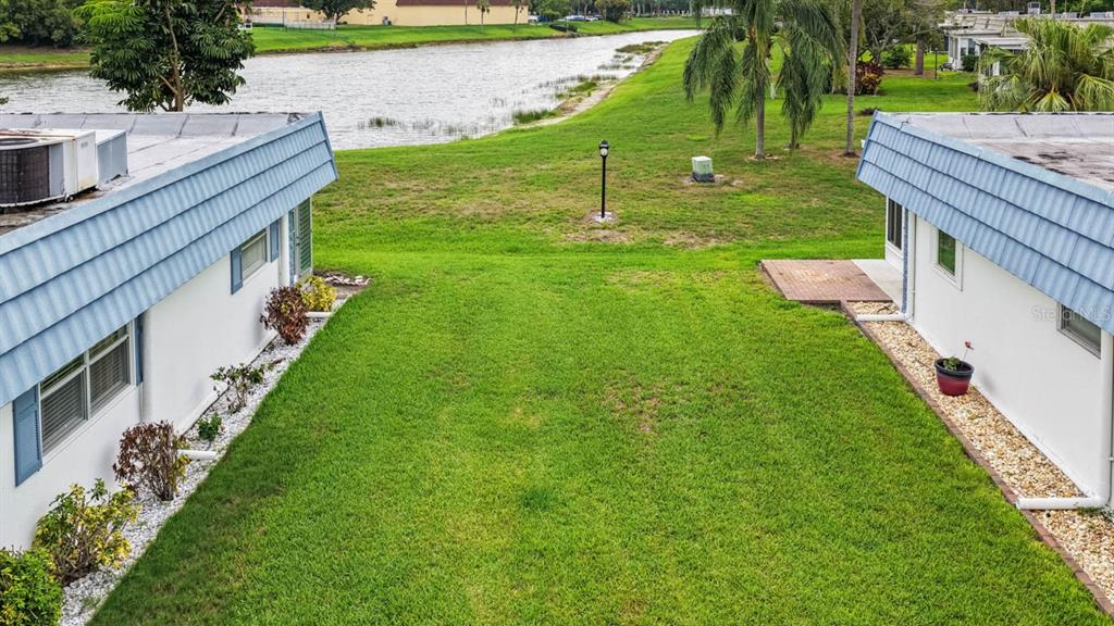 An aerial view shows a grassy yard between two white buildings with blue roofs — 1901 ANDOVER WAY UNIT 38, SUN CITY CENTER, FL