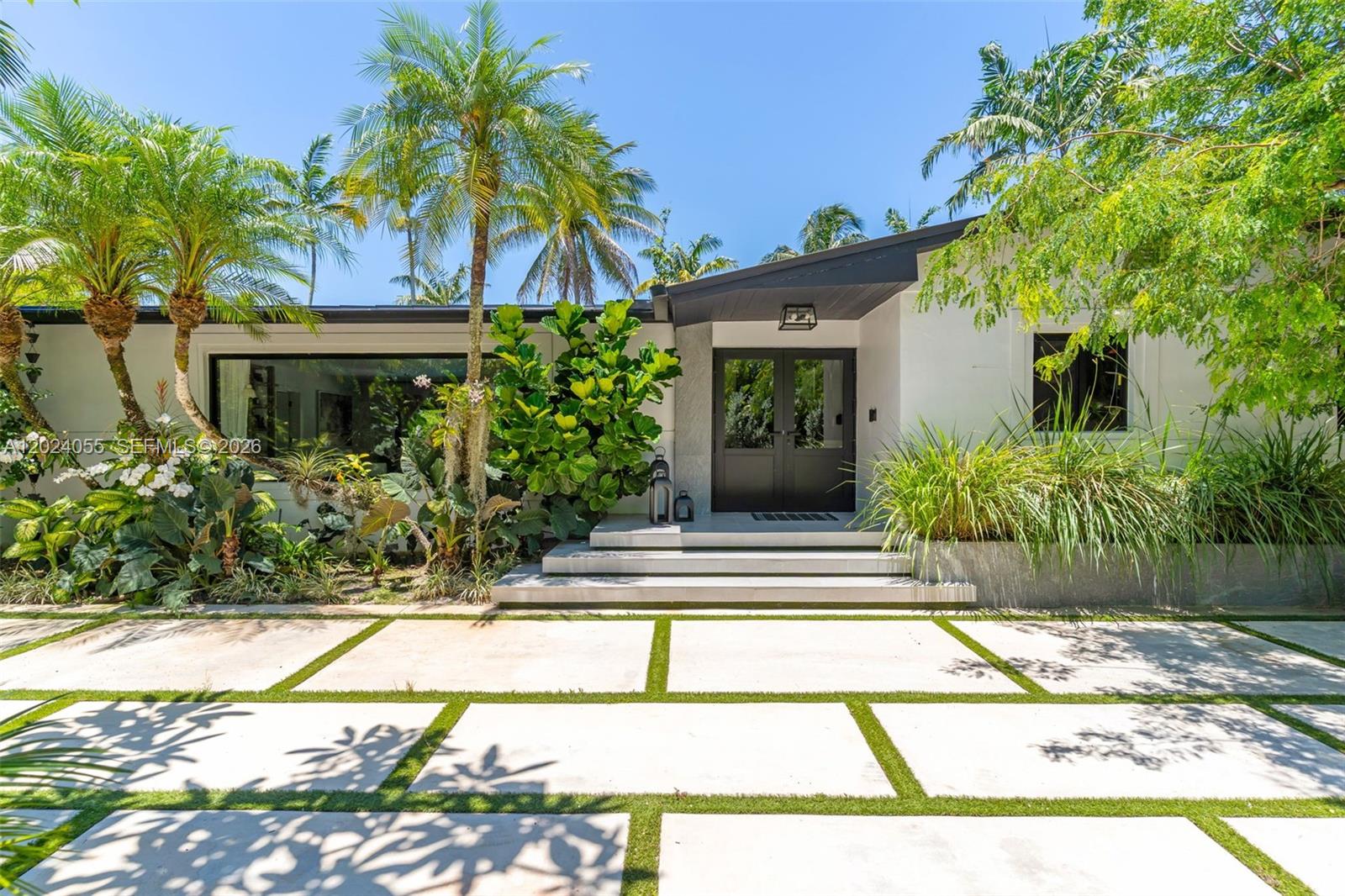 The exterior of a modern house features a paved driveway with grass strips and palm trees — 13400 SW 70th Ave, Pinecrest FL 33156, PINECREST, FL