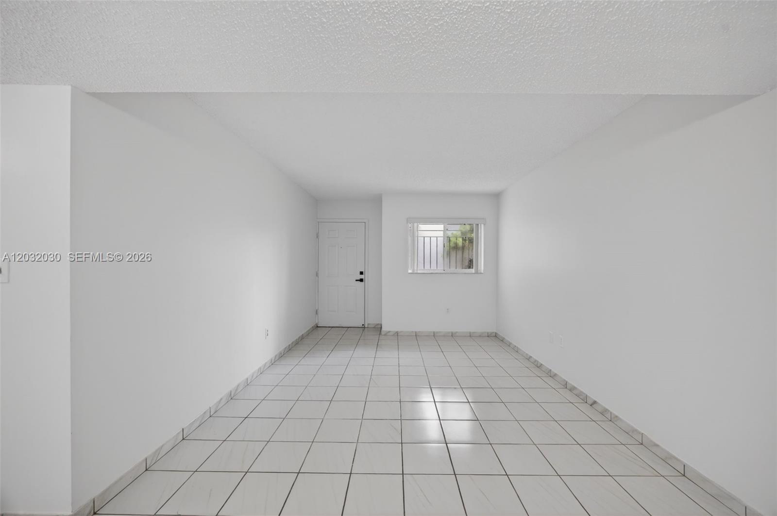 An empty room with white walls, a white door, a window, and white tiled flooring — 800 SW 104th Ct # 103, Miami FL 33174, MIAMI, FL