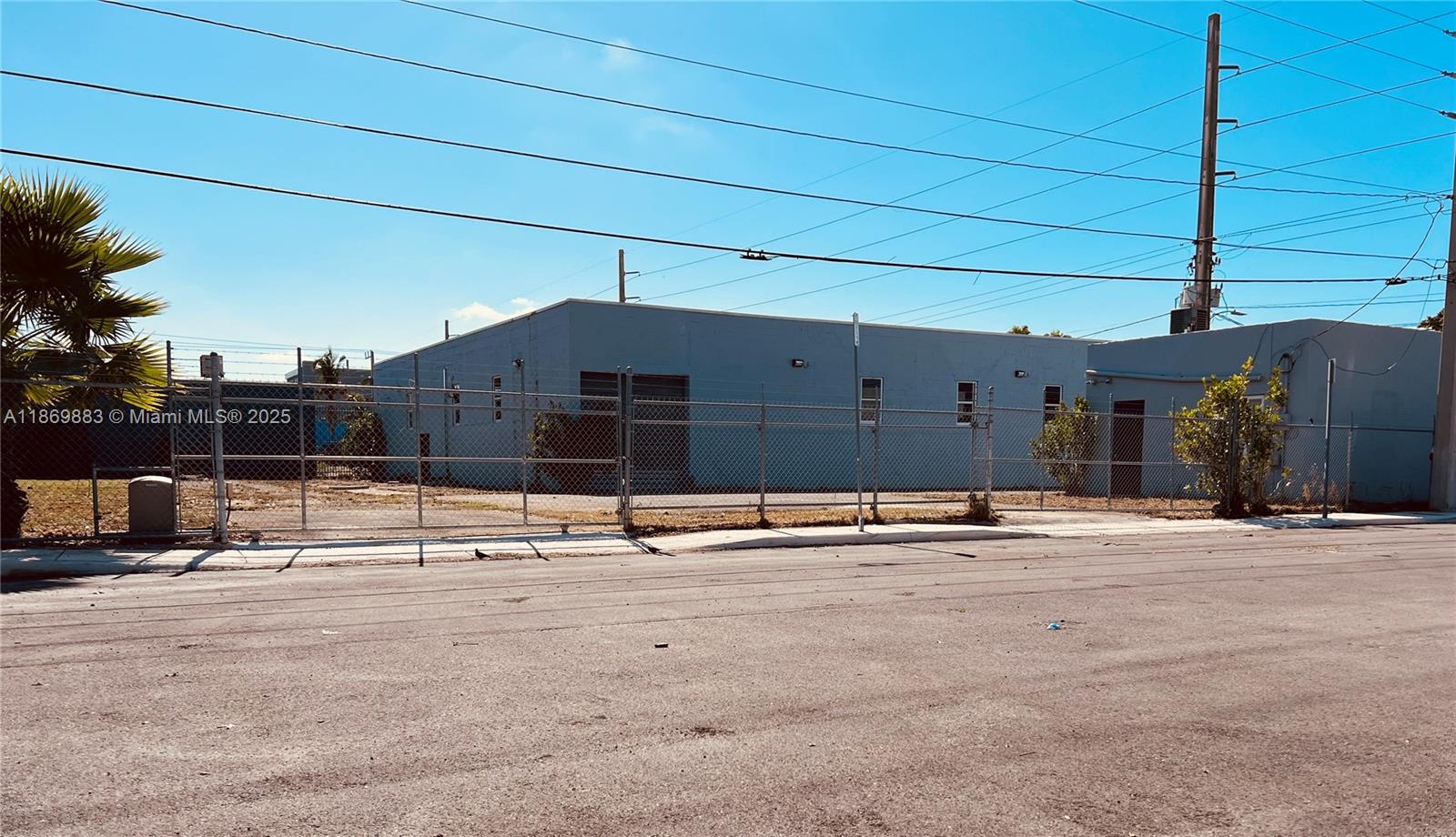 A single-story commercial building with a chain-link fence sits behind a paved street — 1031 NW 21st St, Miami FL 33127, MIAMI, FL