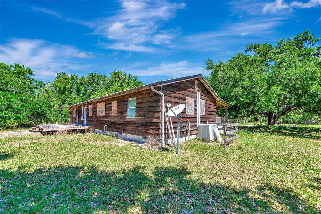 A wooden house with a satellite dish and a deck stands in a grassy yard — 15750 WILSON ROAD, SARASOTA, FL