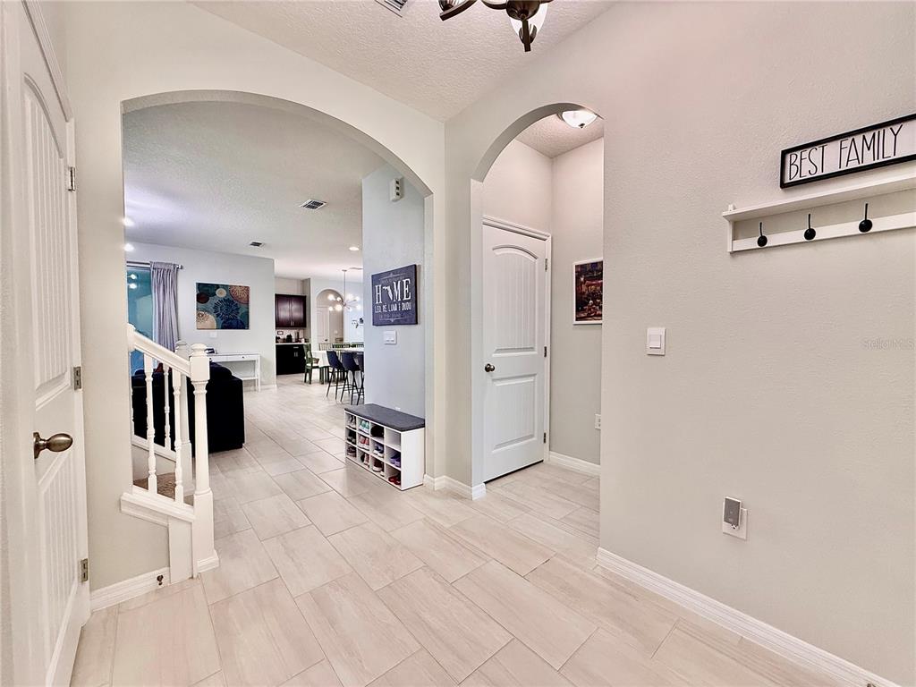A bright entryway features light tile flooring, arched doorways, and a white shoe storage bench — 17098 WATER SPRING BOULEVARD, WINTER GARDEN, FL