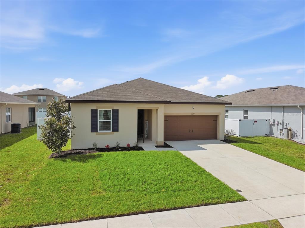 A single-story house with a tan exterior, dark shutters, and a two-car garage — 5629 WESTERN SUN DRIVE, ST CLOUD, FL