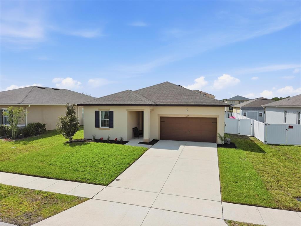 A single-story house with a brown garage door, tan exterior, and a concrete driveway — 5629 WESTERN SUN DRIVE, ST CLOUD, FL