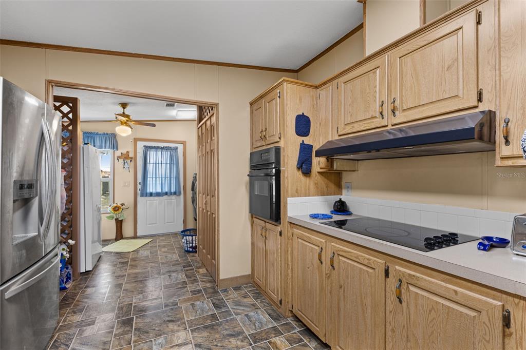 A kitchen with oak cabinets, a built-in oven, a glass cooktop, and tile flooring — 6689 SE 55TH STREET, TRENTON, FL