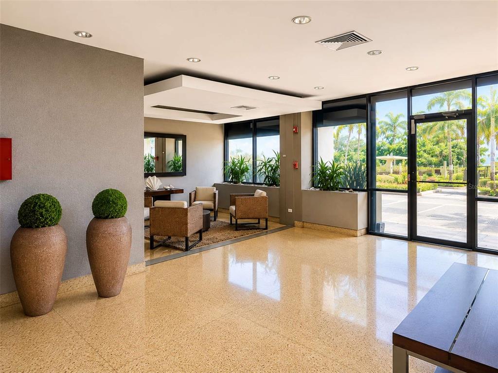 A modern lobby features polished terrazzo floors, recessed lighting, and a seating area with plants — 4745 AVE ISLA VERDE UNIT 4-D, CAROLINA, PR