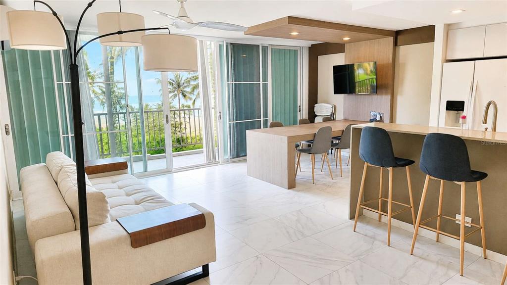 A modern living and dining area with white marble floors and a balcony overlooking trees — 4745 AVE ISLA VERDE UNIT 4-D, CAROLINA, PR