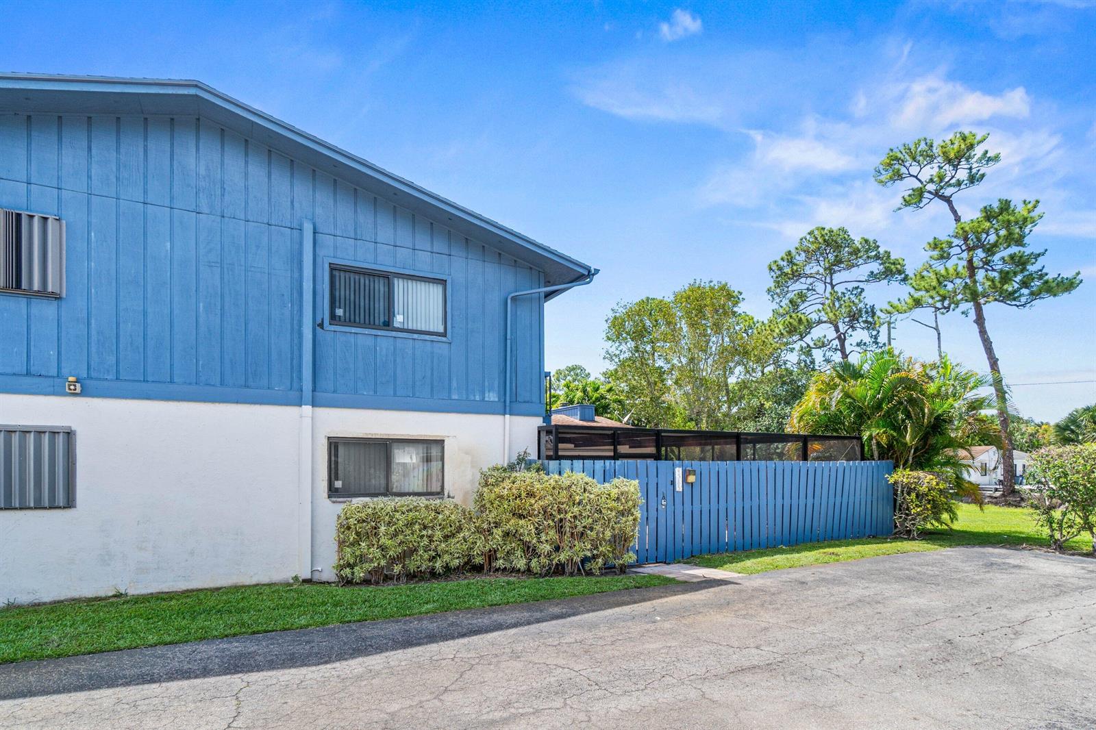 A two-story blue and white building features a fenced side yard and a paved driveway — 4585 Holly Lake Drive, Lake Worth FL 33463, LAKE WORTH, FL