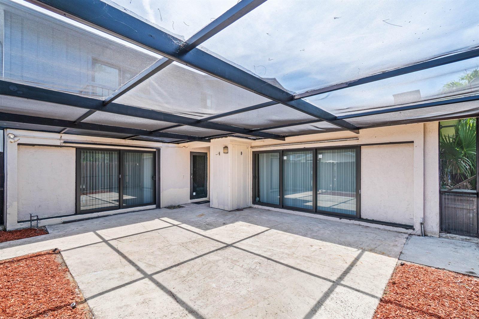 A covered concrete patio features sliding glass doors and a screen enclosure — 4585 Holly Lake Drive, Lake Worth FL 33463, LAKE WORTH, FL