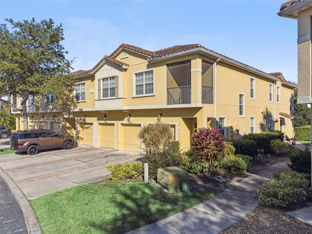 A multi-story yellow stucco townhouse with a tile roof and attached garages — 2841 OAKWATER DRIVE, KISSIMMEE, FL