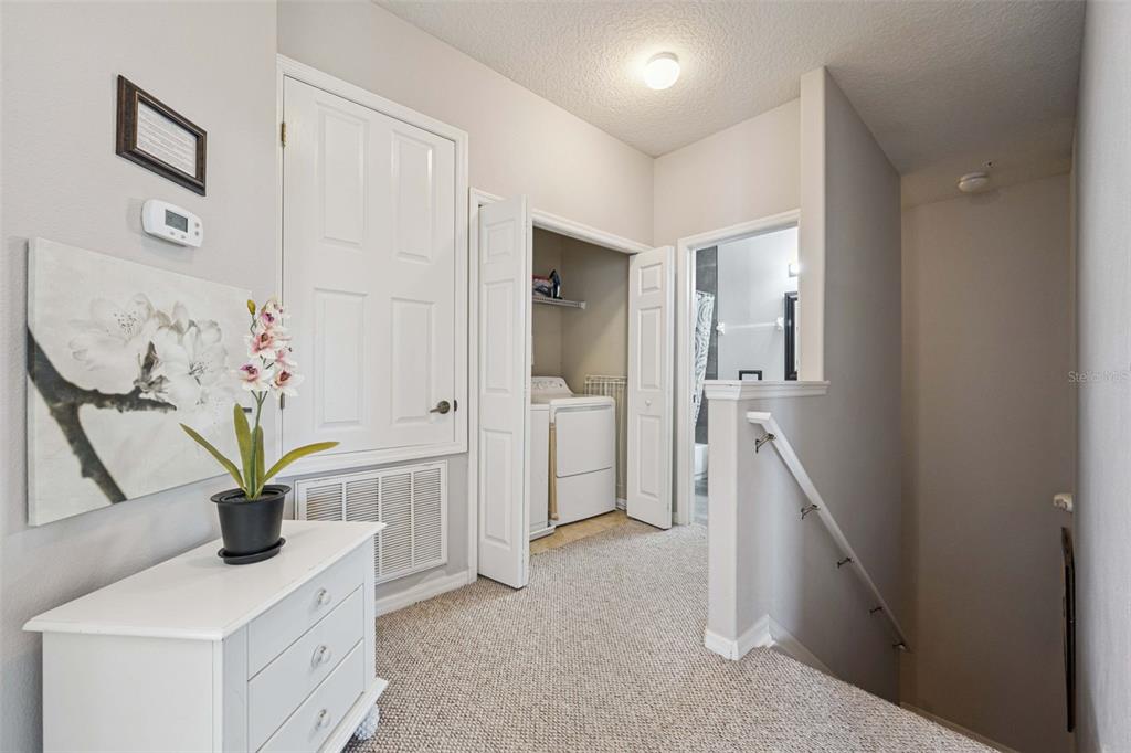 A carpeted hallway features a laundry closet, a bathroom entrance, and a staircase — 2841 OAKWATER DRIVE, KISSIMMEE, FL