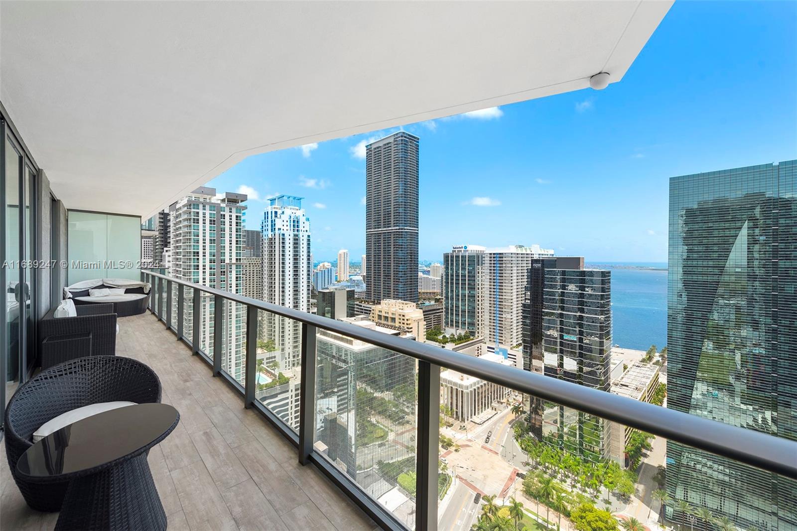 A balcony with outdoor furniture overlooks a dense city skyline and a body of water — 1300 S Miami Ave # 3402, Miami FL 33130, MIAMI, FL