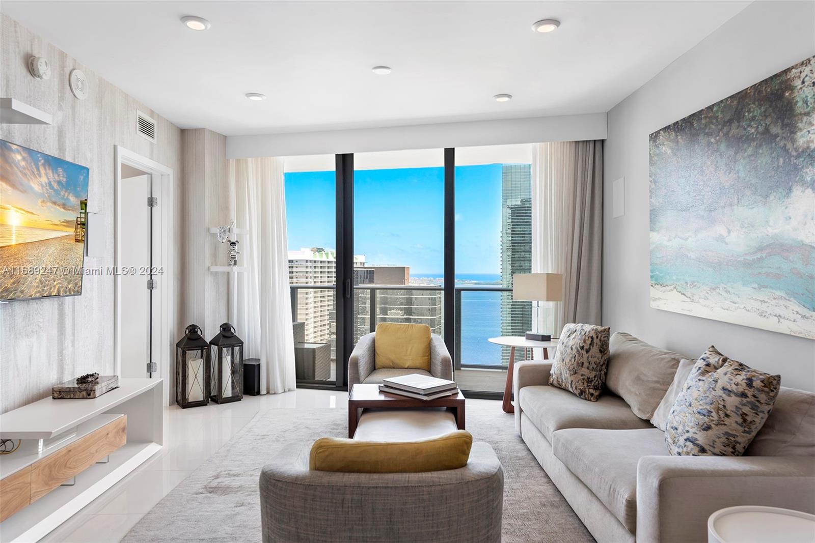 A living room features a sofa, armchairs, a television, and floor-to-ceiling windows overlooking the ocean — 1300 S Miami Ave # 3402, Miami FL 33130, MIAMI, FL