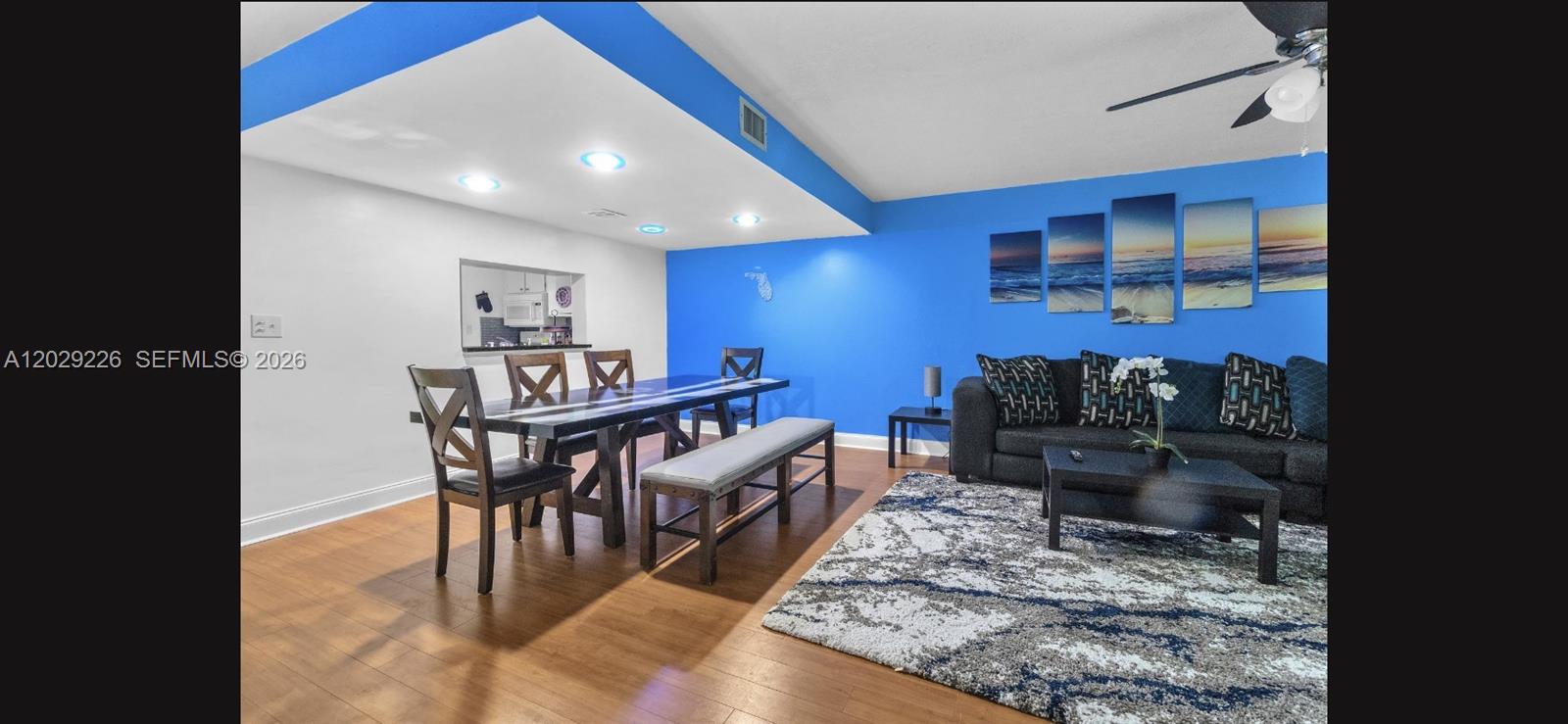 A dining and living area features blue accent walls, wood flooring, and a large rug — 9427 NW 42nd St, Sunrise FL 33351, SUNRISE, FL