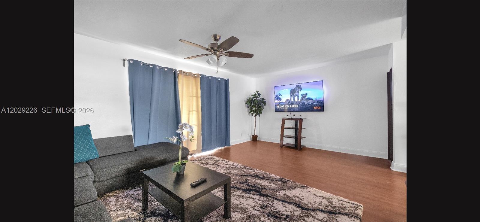 A living room features wood-look flooring, a gray sectional sofa, and a wall-mounted television — 9427 NW 42nd St, Sunrise FL 33351, SUNRISE, FL