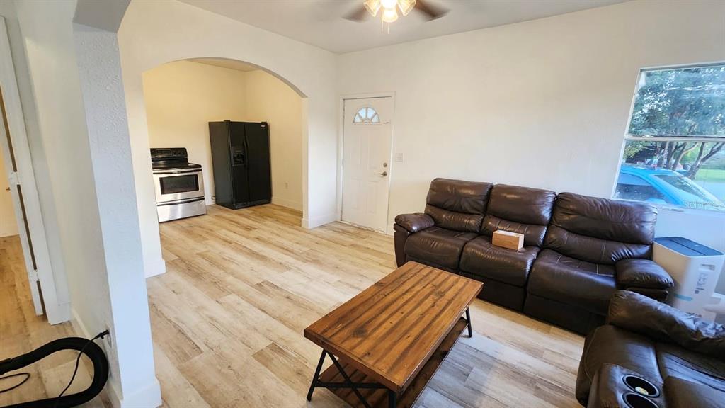 A living room with wood-look flooring and a brown leather sofa leads into a kitchen — 412 BAY STREET NW, FORT MEADE, FL