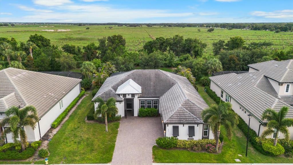 An aerial view shows a single-story house with a tiled roof and a paved driveway — 6325 RIVO LAKES BOULEVARD, SARASOTA, FL
