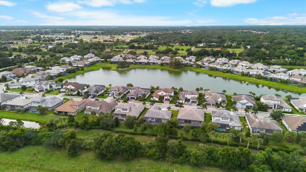 An aerial view of a suburban neighborhood featuring houses surrounding a central lake — 6325 RIVO LAKES BOULEVARD, SARASOTA, FL