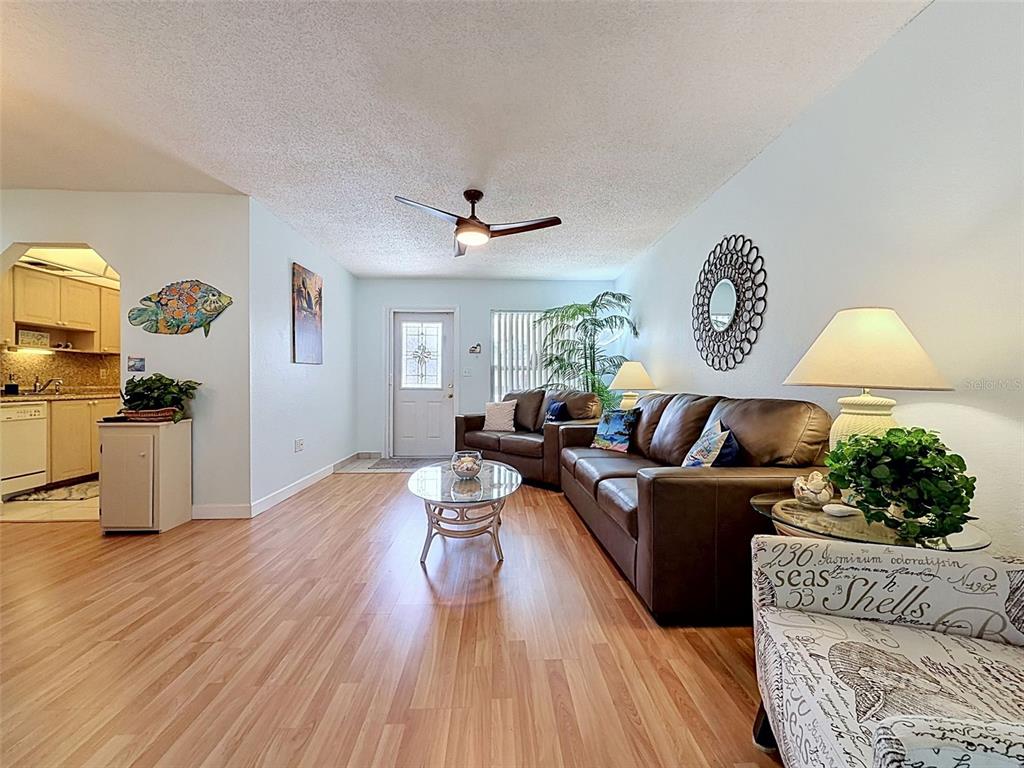 A living room with wood-look flooring, a ceiling fan, and brown leather furniture — 11935 BOYNTON LANE UNIT 17GB, NEW PORT RICHEY, FL